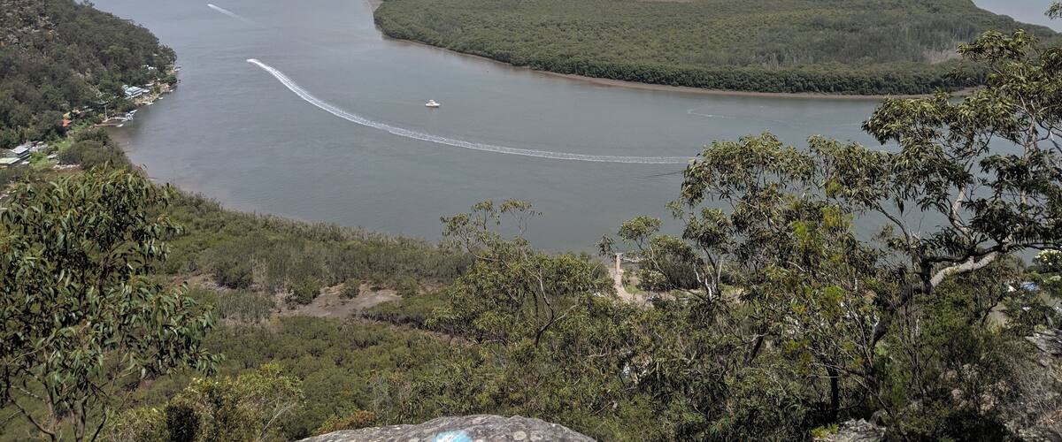 A river winding through a mountainous landscape with dense forests and a small settlement along the banks.