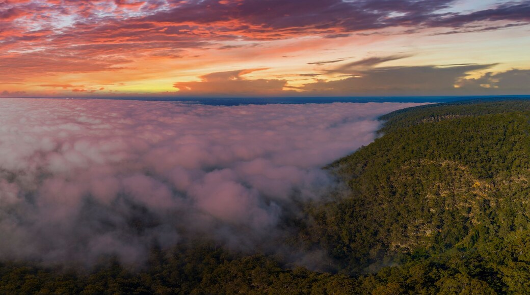 A mountainous landscape with a cloud-covered valley and a sunset sky.