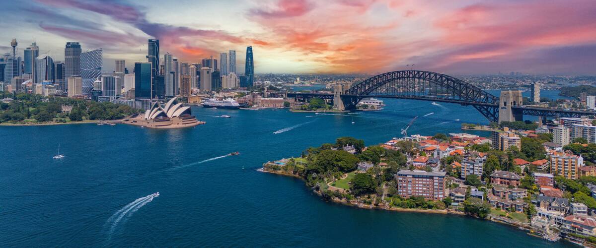 A cityscape with a prominent bridge, a waterfront, and the Sydney Opera House.