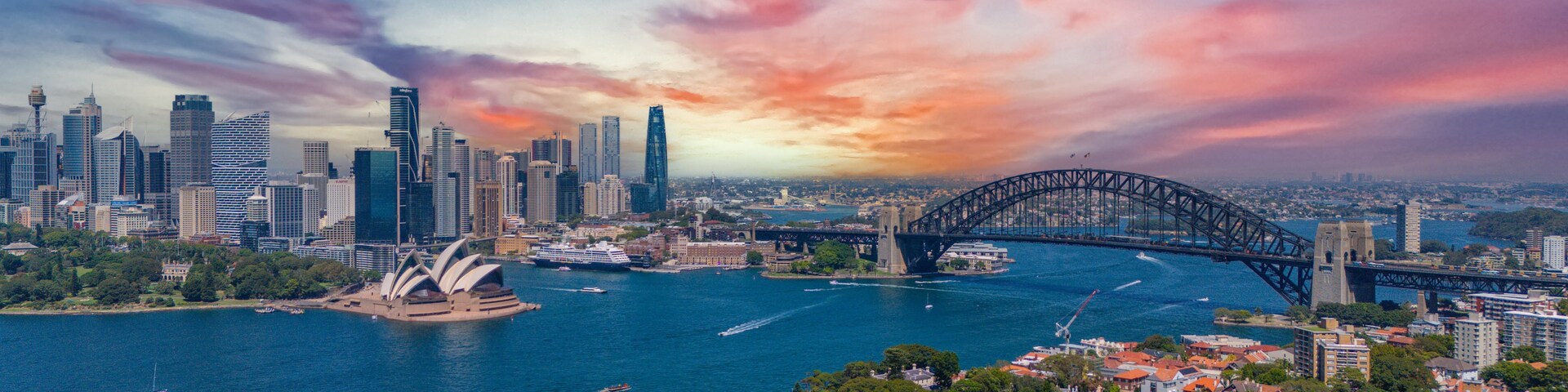 A cityscape with a prominent bridge, a waterfront, and the Sydney Opera House.