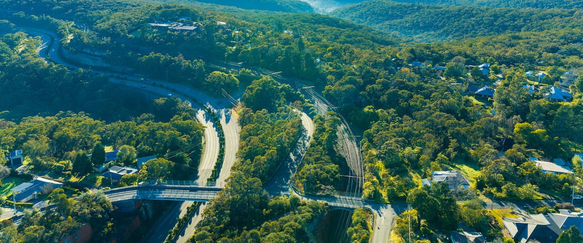 A river winding through a valley with scattered houses and a bridge.