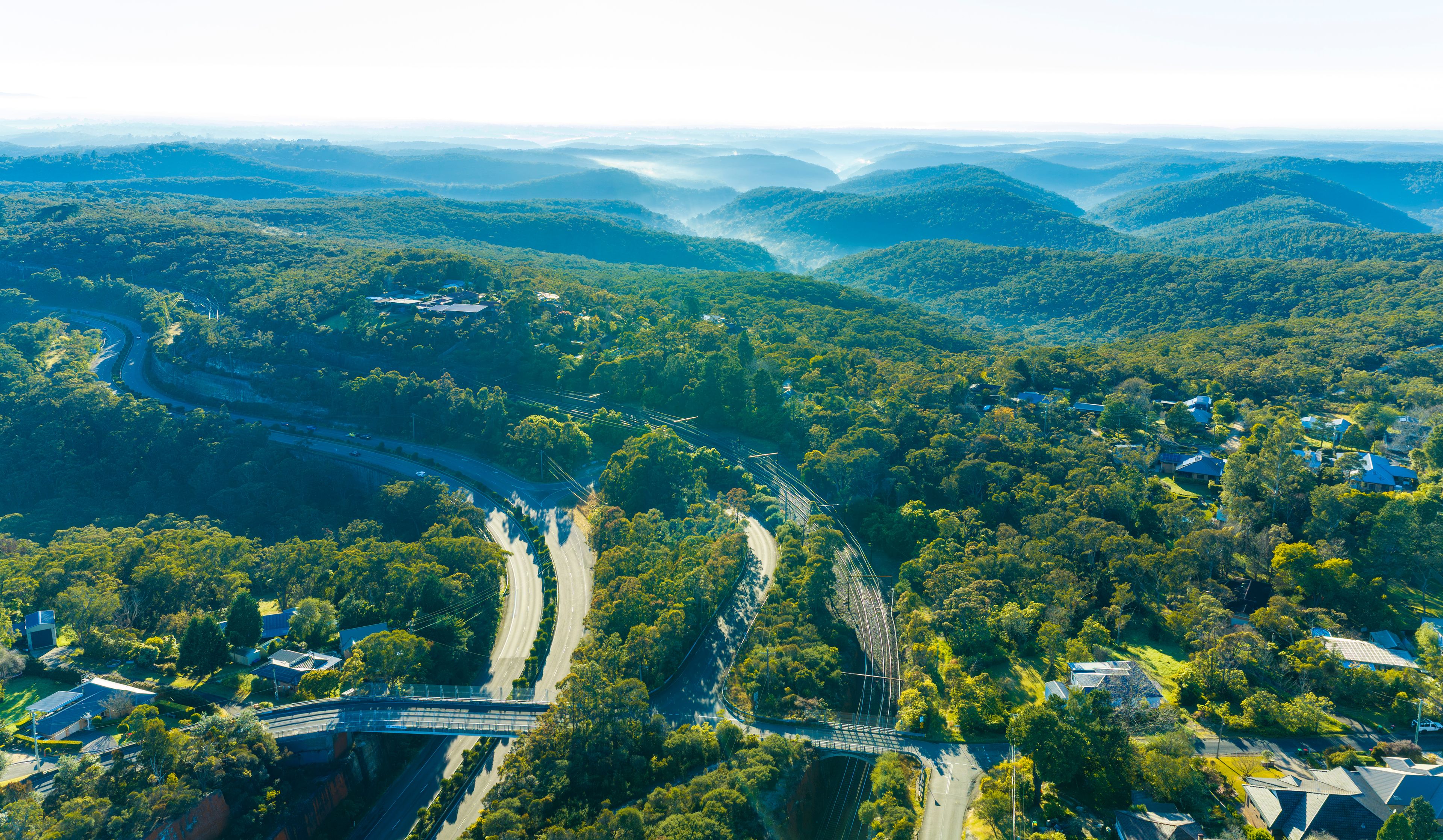 A river winding through a valley with scattered houses and a bridge.