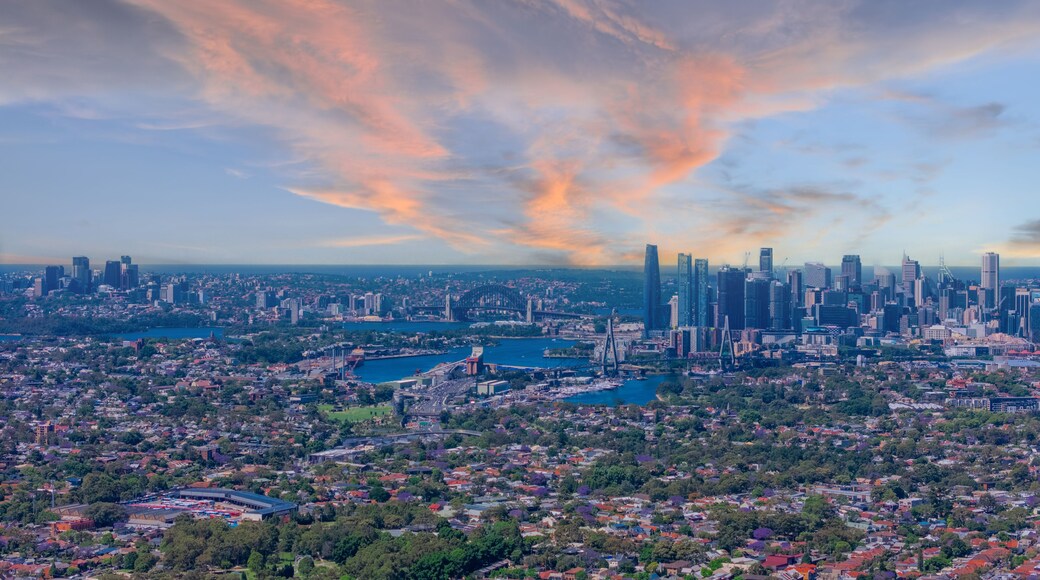 A cityscape with a prominent skyline, a large body of water, and surrounding greenery.