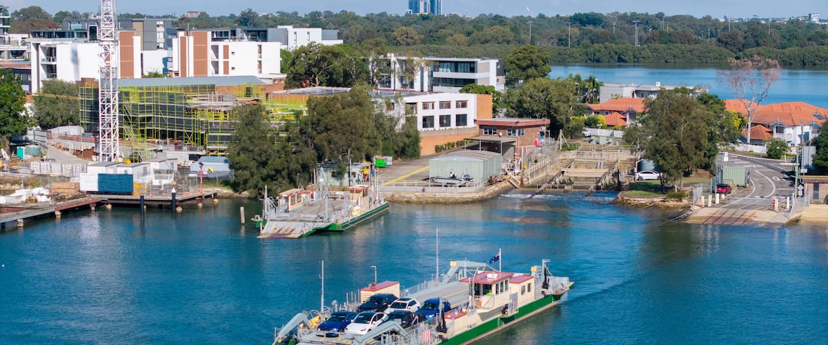 A green and white ferry docked at a pier with a cityscape in the background.
