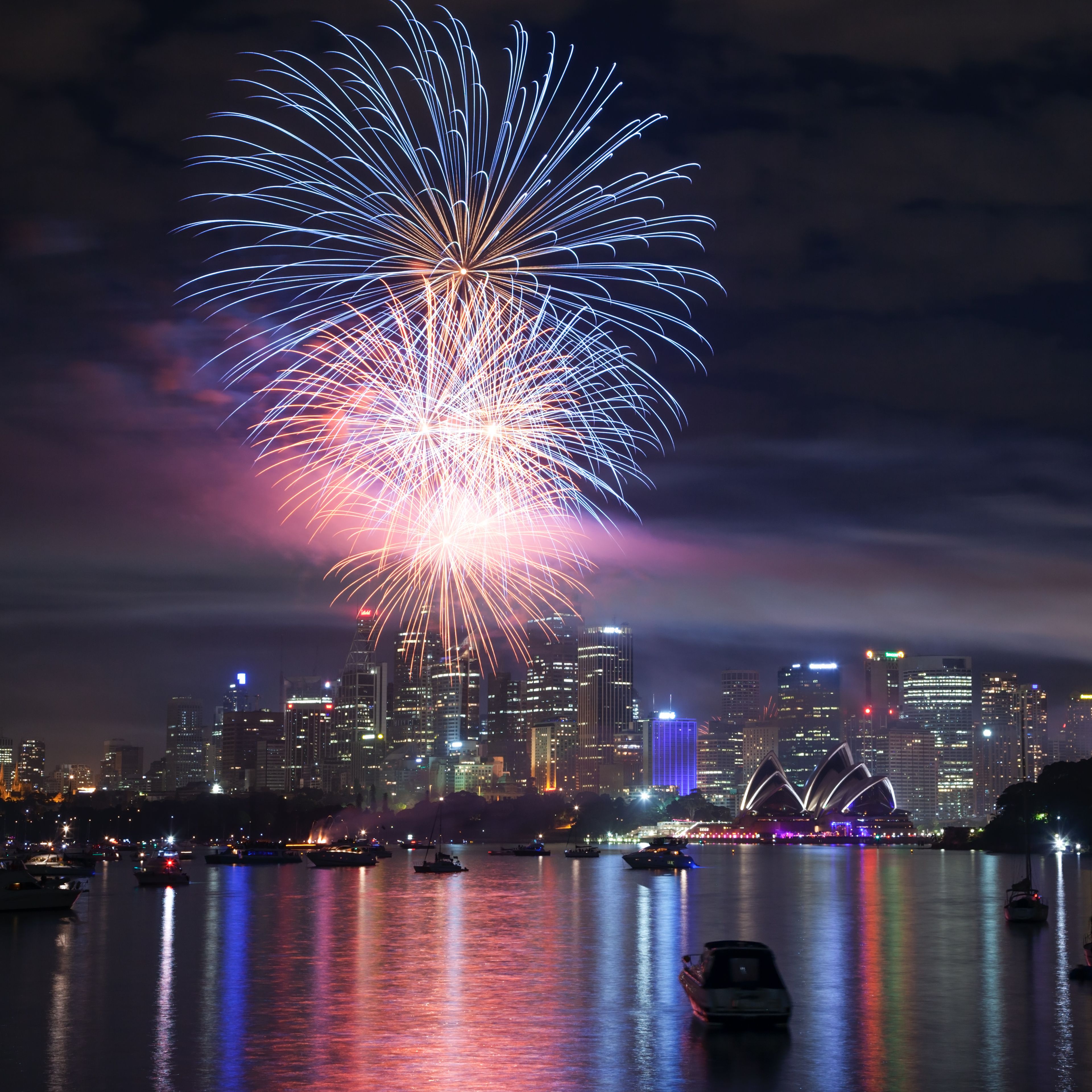 A city skyline with fireworks over a body of water.