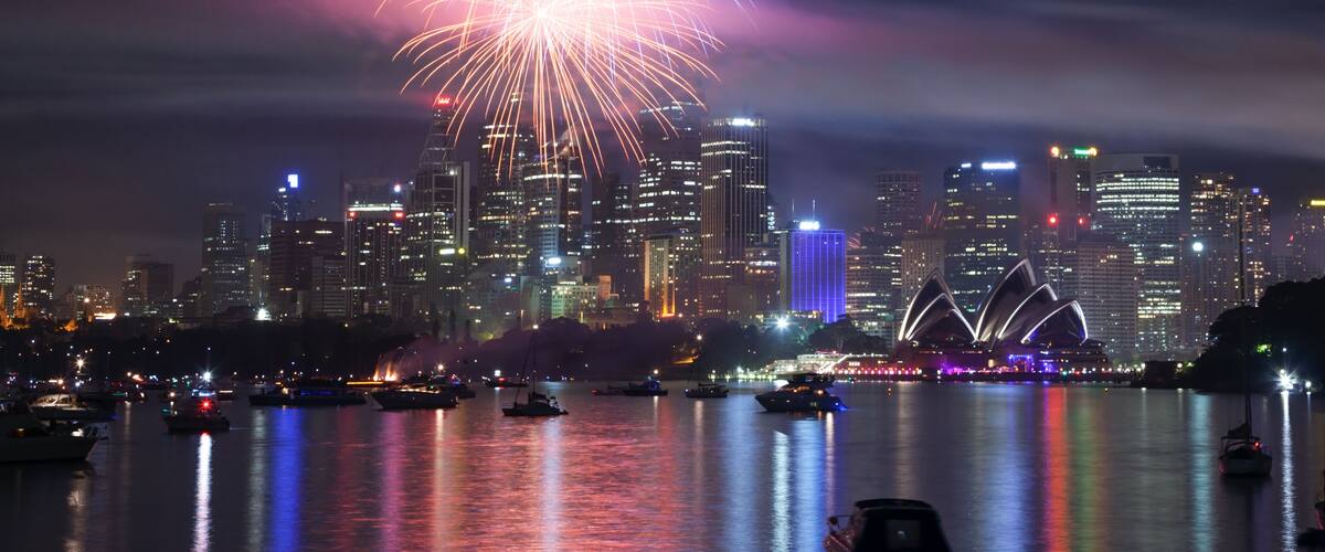 A city skyline with fireworks over a body of water.