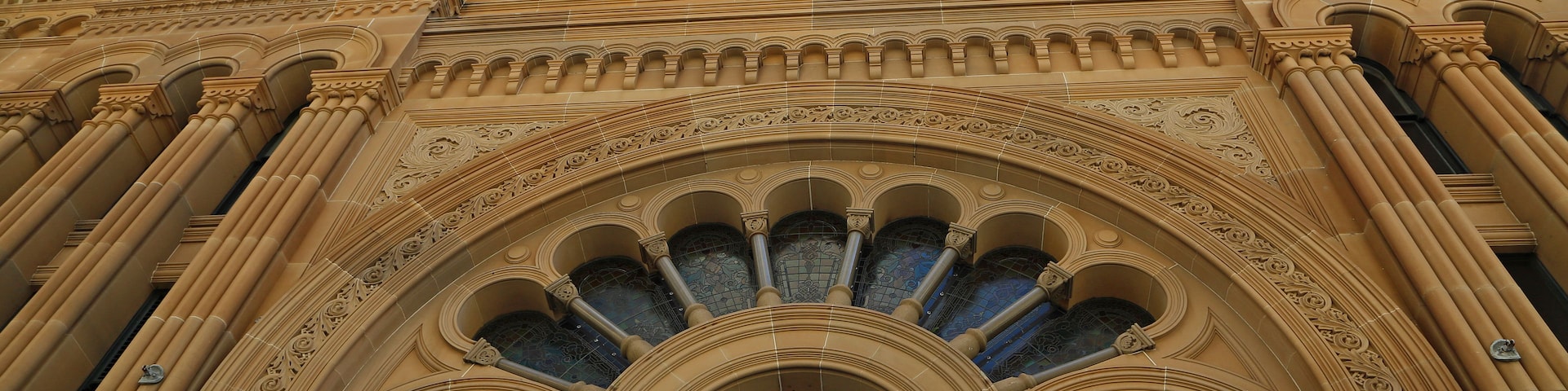 Um edifício ornamentado com detalhes arquitetônicos elaborados, incluindo uma grande entrada em arco e colunas decorativas.