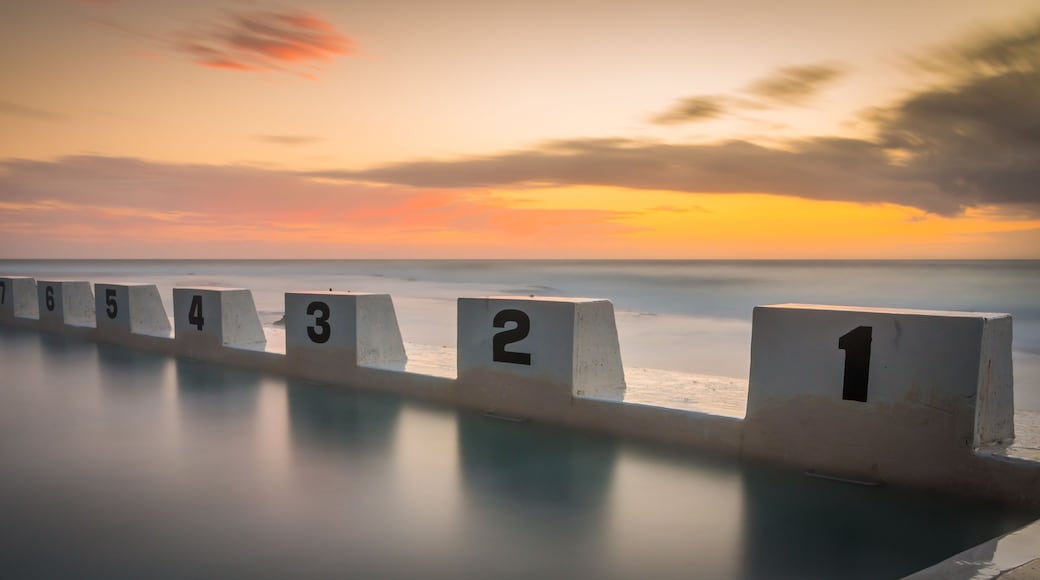 A series of numbered concrete blocks along a shoreline at sunset.