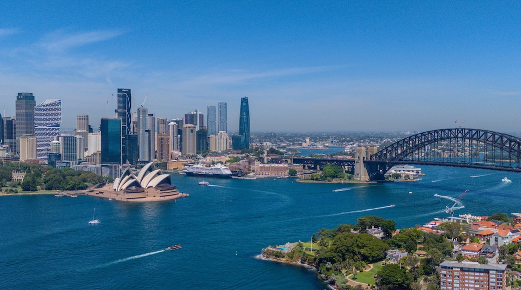 A city skyline with modern skyscrapers, a prominent bridge, and the Sydney Opera House.