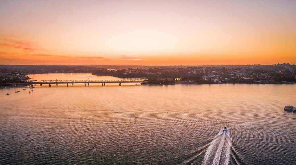 A sunset over a river with a bridge and a cityscape in the background.