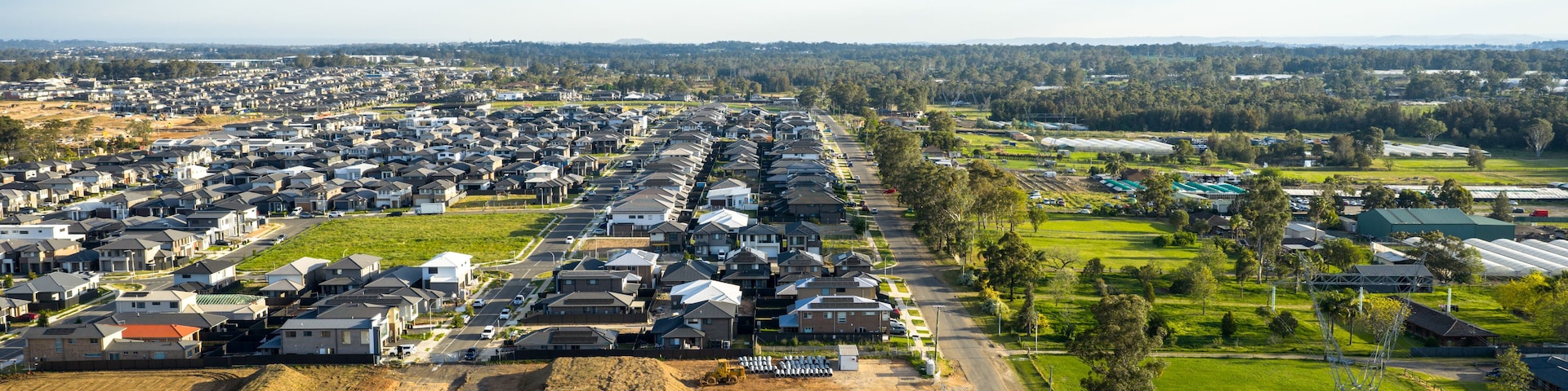 A residential area with houses, a road, and agricultural fields.