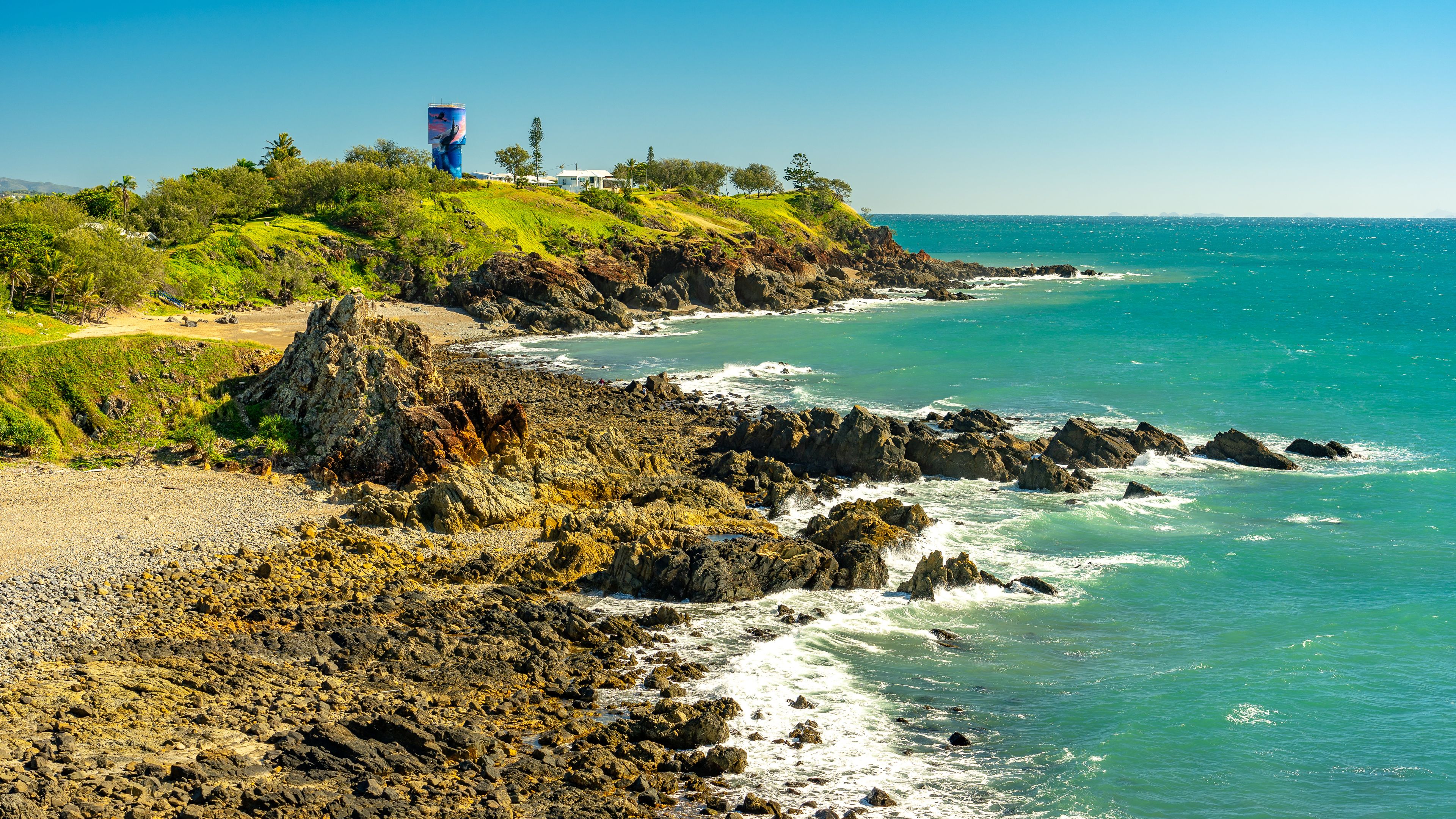 A coastal landscape with rocky shores, a grassy hill, and a large billboard.