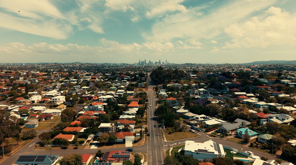 An aerial view of a residential area with houses, roads, and a distant city skyline.