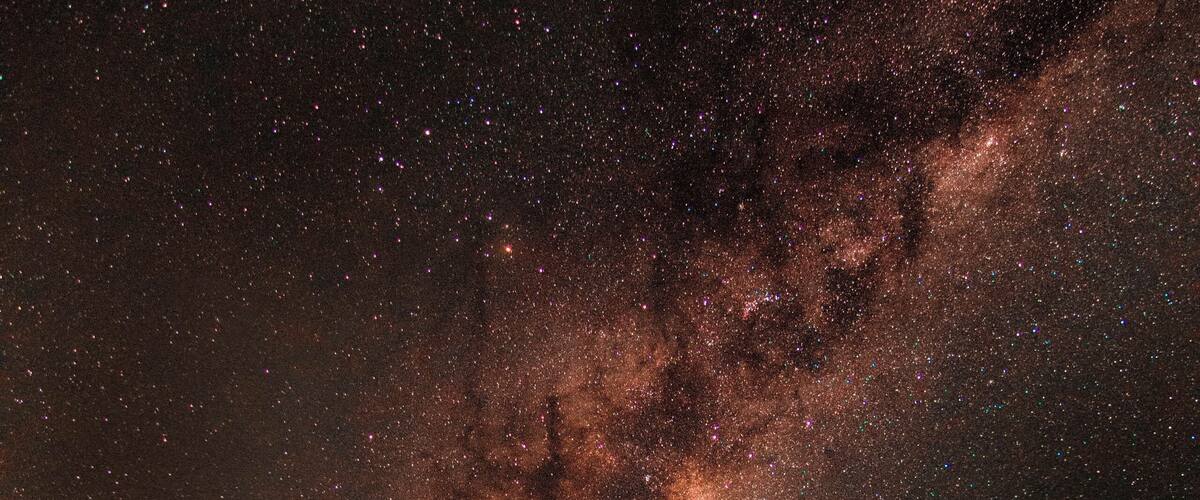 A rural road at night with a starry sky and the Milky Way visible.
