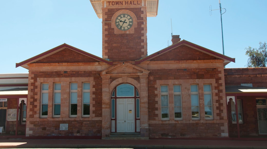 A brick town hall with a clock tower, arched entrance, and a sign reading 'Town Hall.'