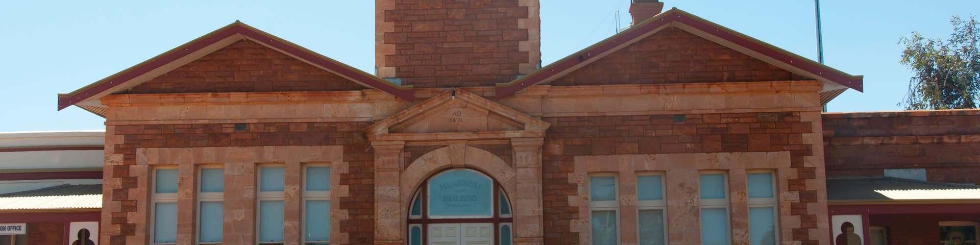 A brick town hall with a clock tower, arched entrance, and a sign reading 'Town Hall.'
