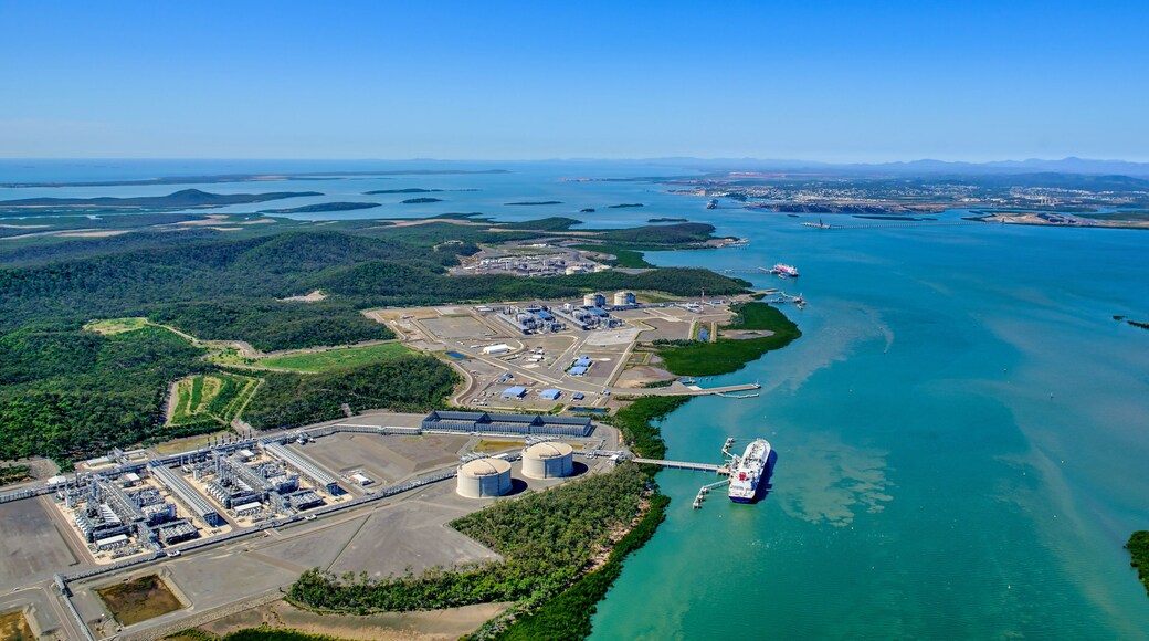 Un puerto industrial con un gran barco de carga atracado, rodeado de agua y vegetación.