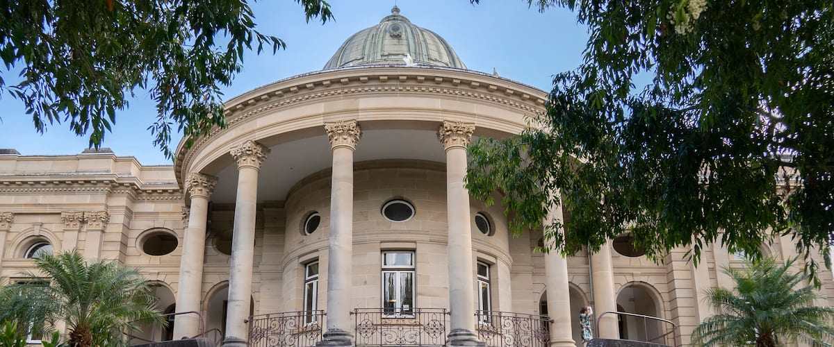 A classical building with a dome, columns, and a staircase leading to the entrance.