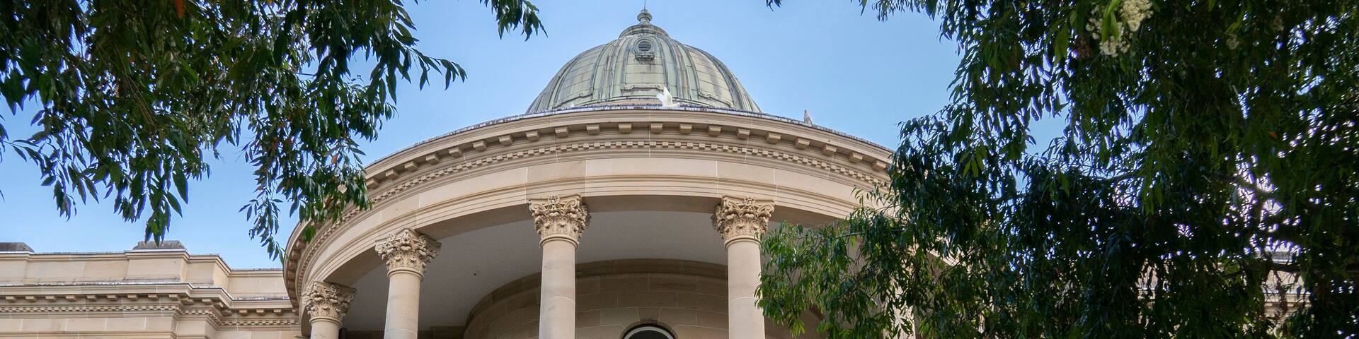 A classical building with a dome, columns, and a staircase leading to the entrance.