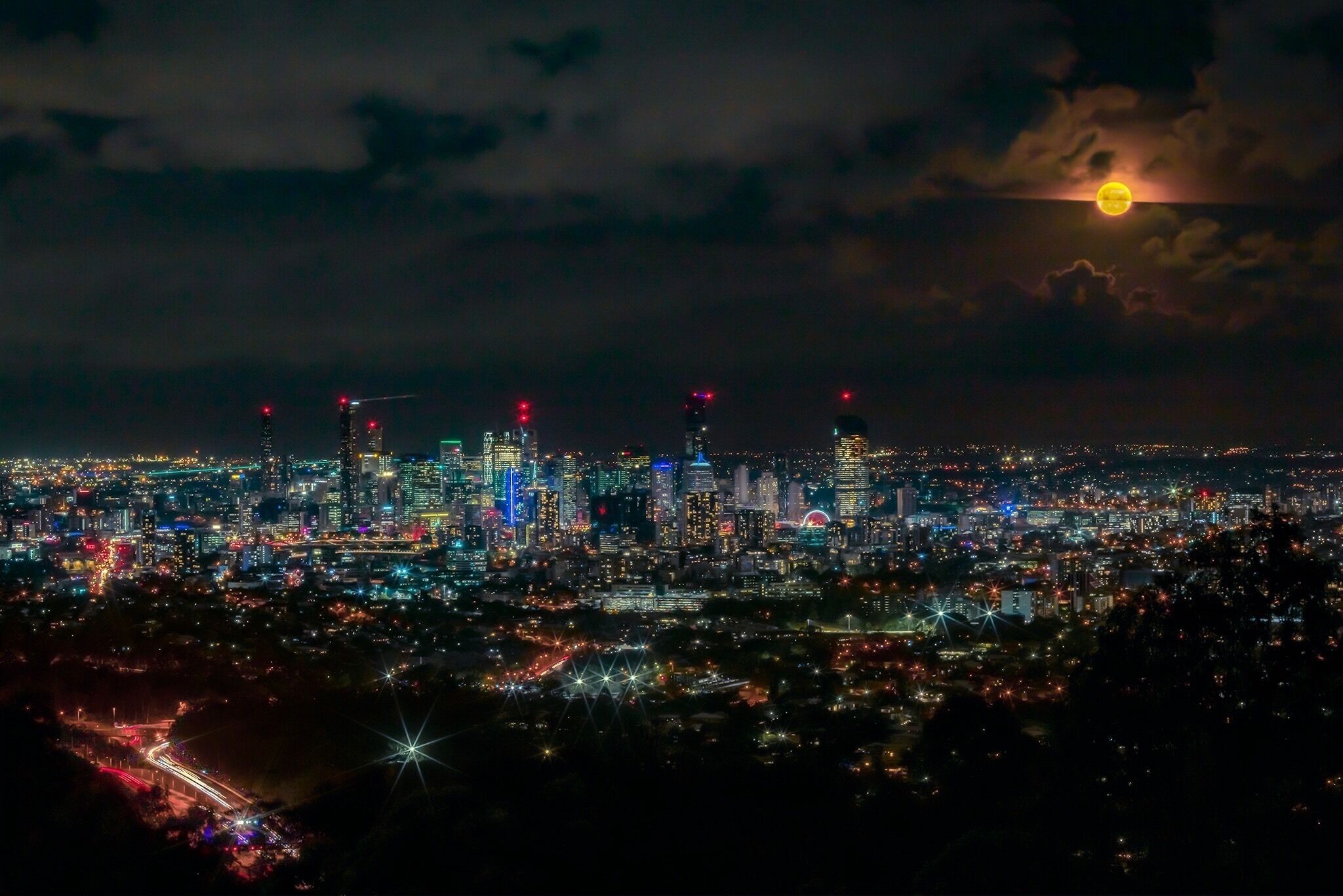 A nighttime cityscape with illuminated buildings and a visible moon.