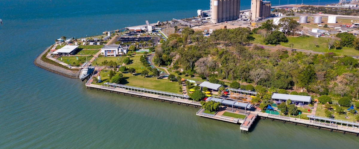 An industrial area with large storage tanks, a bridge, and a waterfront.