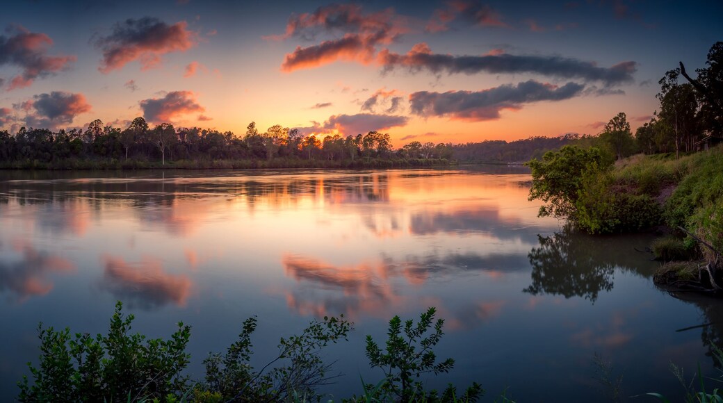 A calm lake at sunset with reflections of the sky and trees.