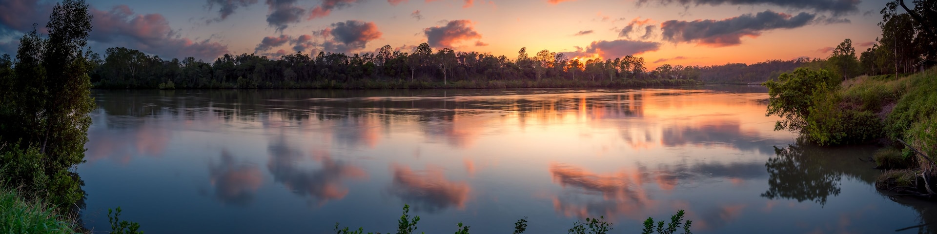 A calm lake at sunset with reflections of the sky and trees.