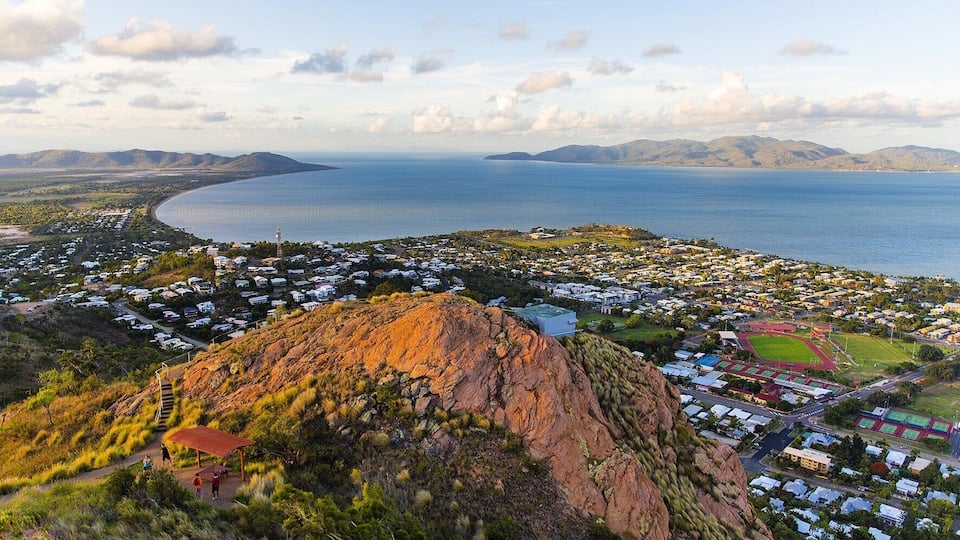 A coastal town with a prominent hill, houses, and a large body of water.