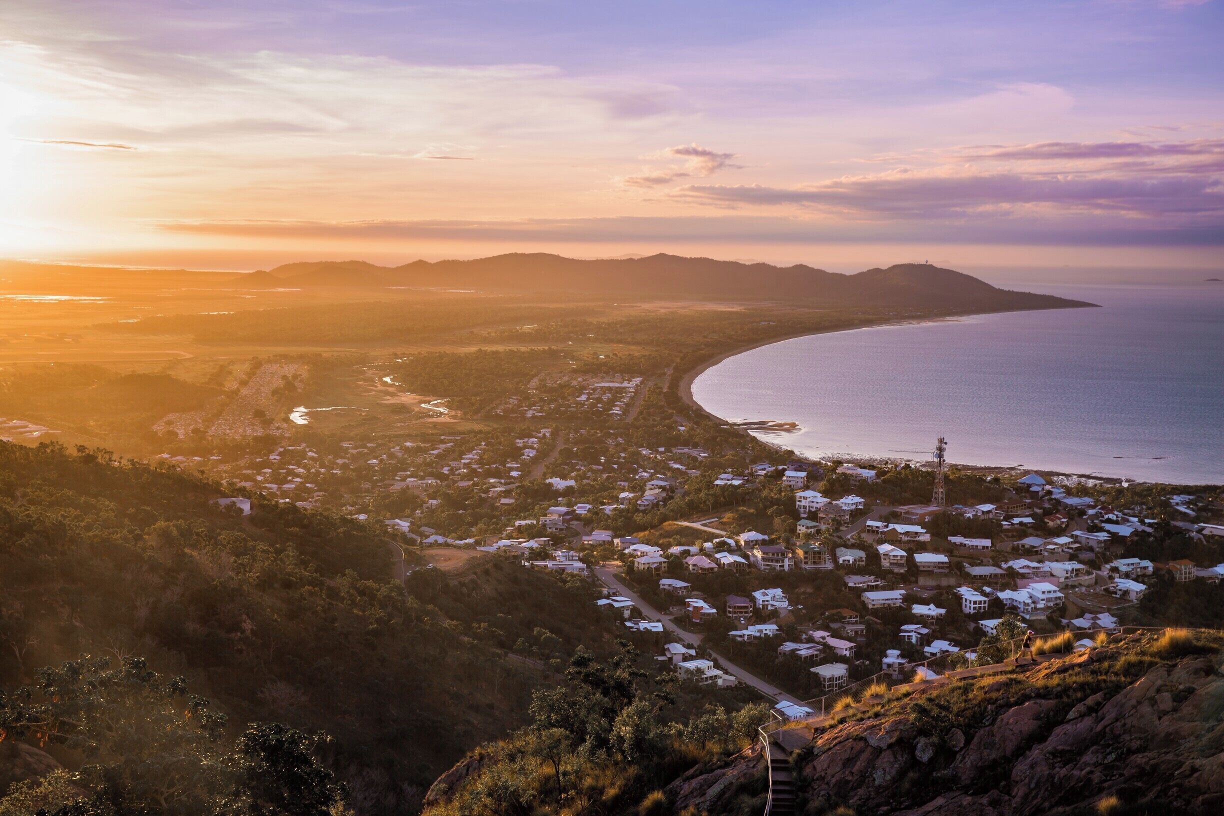 A coastal town with a winding road, houses, and a large body of water.