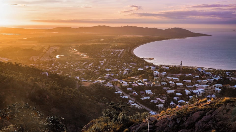 A coastal town with a winding road, houses, and a large body of water.