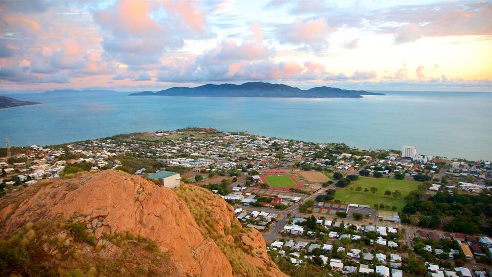 A coastal town with a large body of water, a mountain, and a sports field.