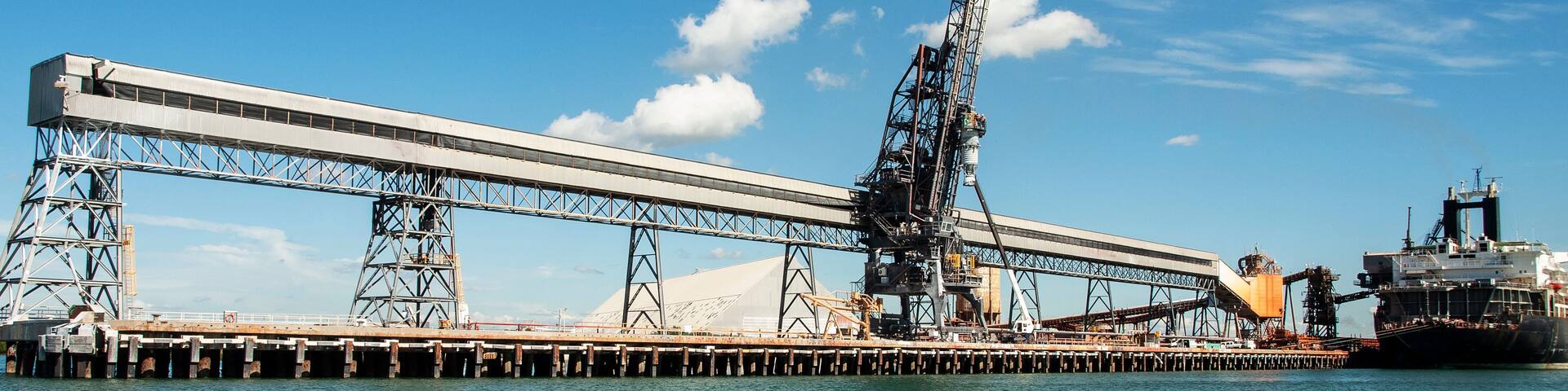 A large industrial pier with cranes and a ship docked.