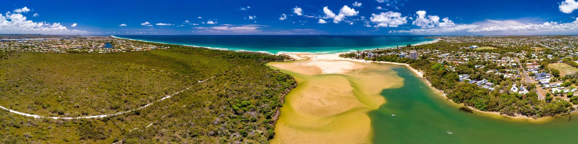 A coastal landscape with a river, beach, and residential area.