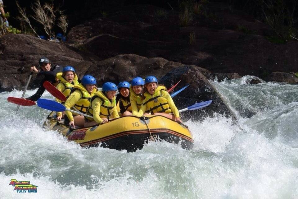 Un gruppo di persone su una zattera gialla che scende un fiume con rapide.
