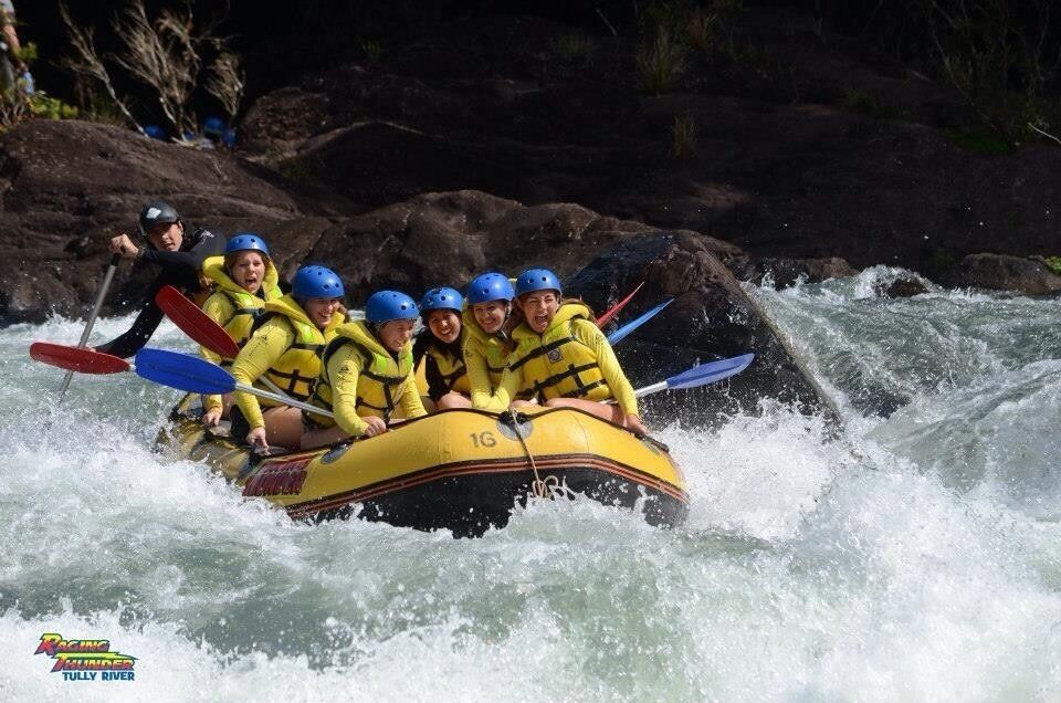 A group of people in a yellow raft navigating a river with rapids.