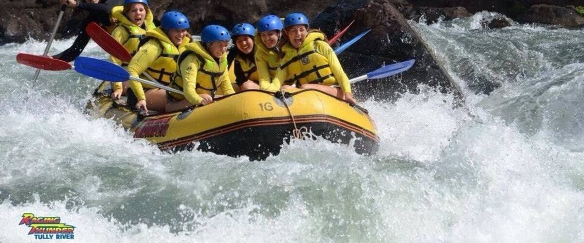 A group of people in a yellow raft navigating a river with rapids.