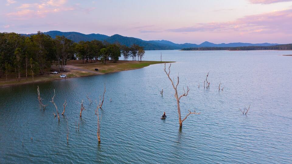 A lake with a boat, trees, and mountains in the background.