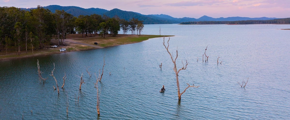 A lake with a boat, trees, and mountains in the background.