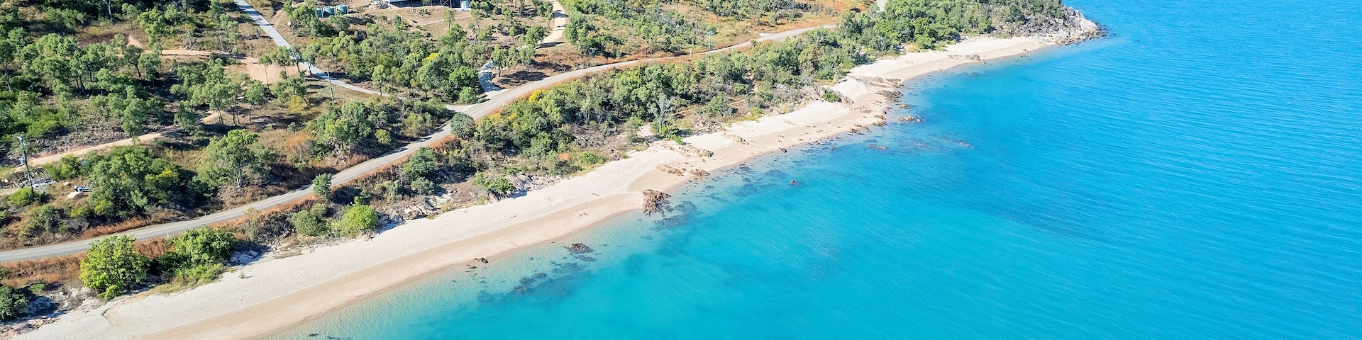 Aerial From Sea Towards Land With House Nestled In Bushland