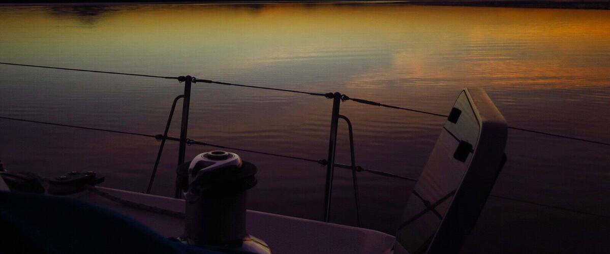 A calm body of water reflecting a sunset with mountains in the distance.
