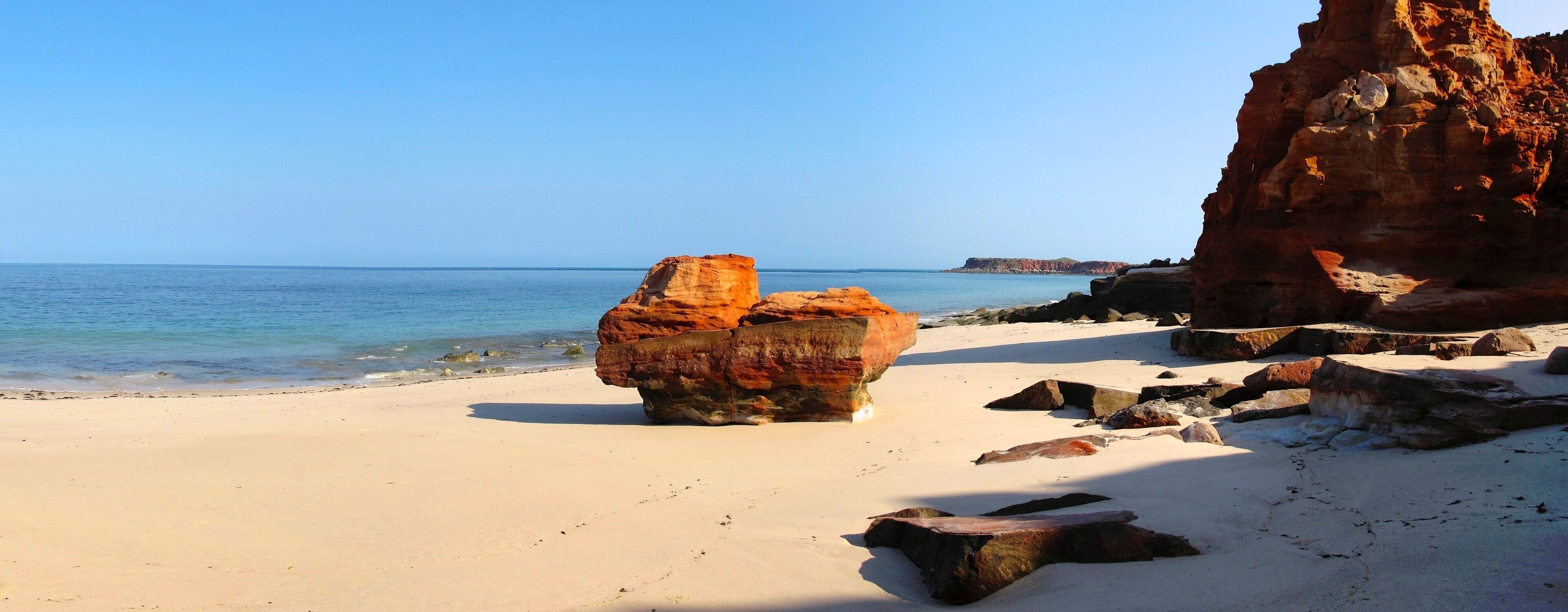 A beach with large rocks and a clear blue sky.