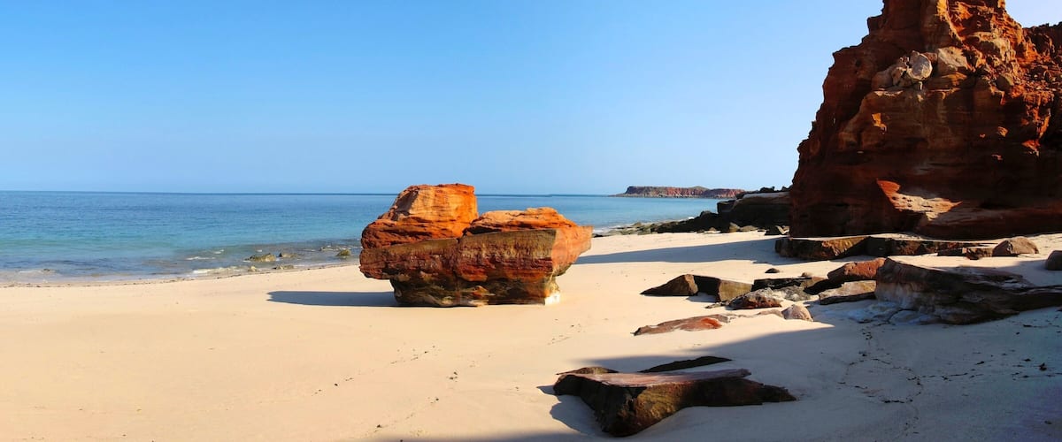 A beach with large rocks and a clear blue sky.