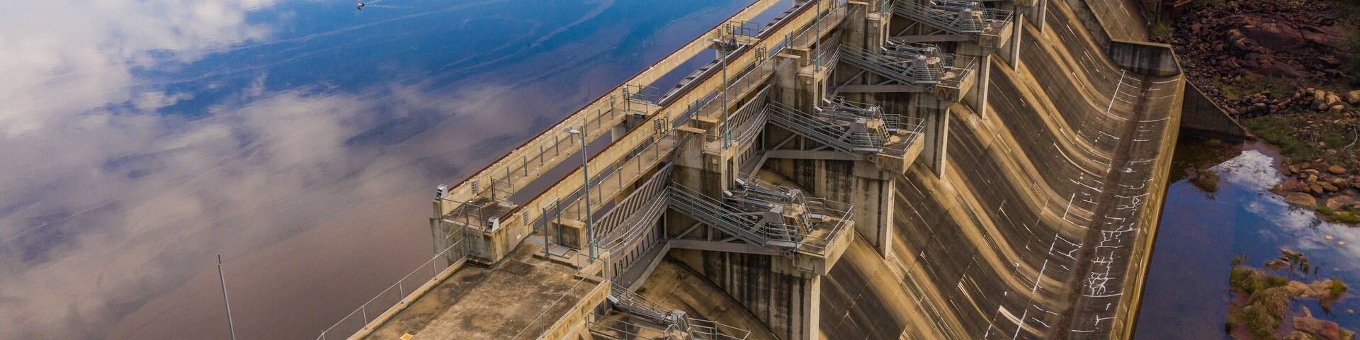 A large dam with multiple spillways and a control tower.