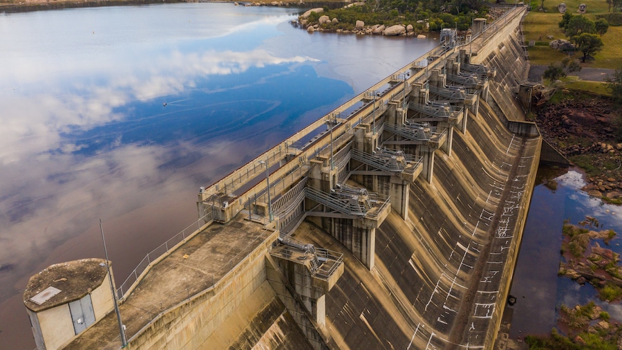 A large dam with multiple spillways and a control tower.