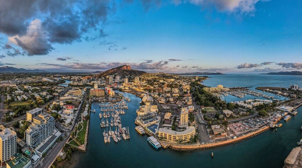 A coastal cityscape with a marina, buildings, and a prominent mountain.