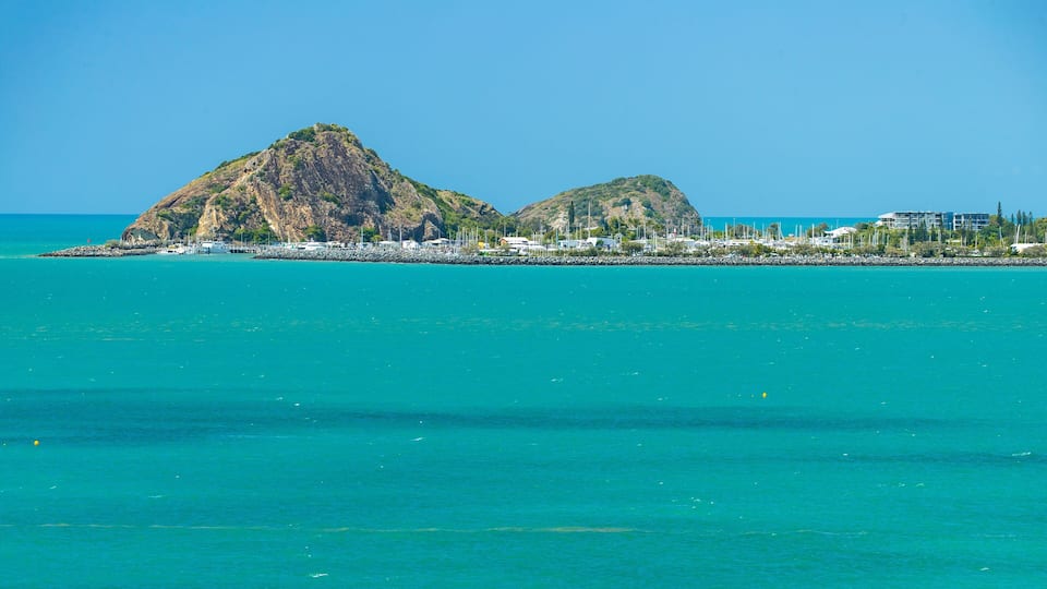 A coastal landscape with two prominent hills and a marina with boats.