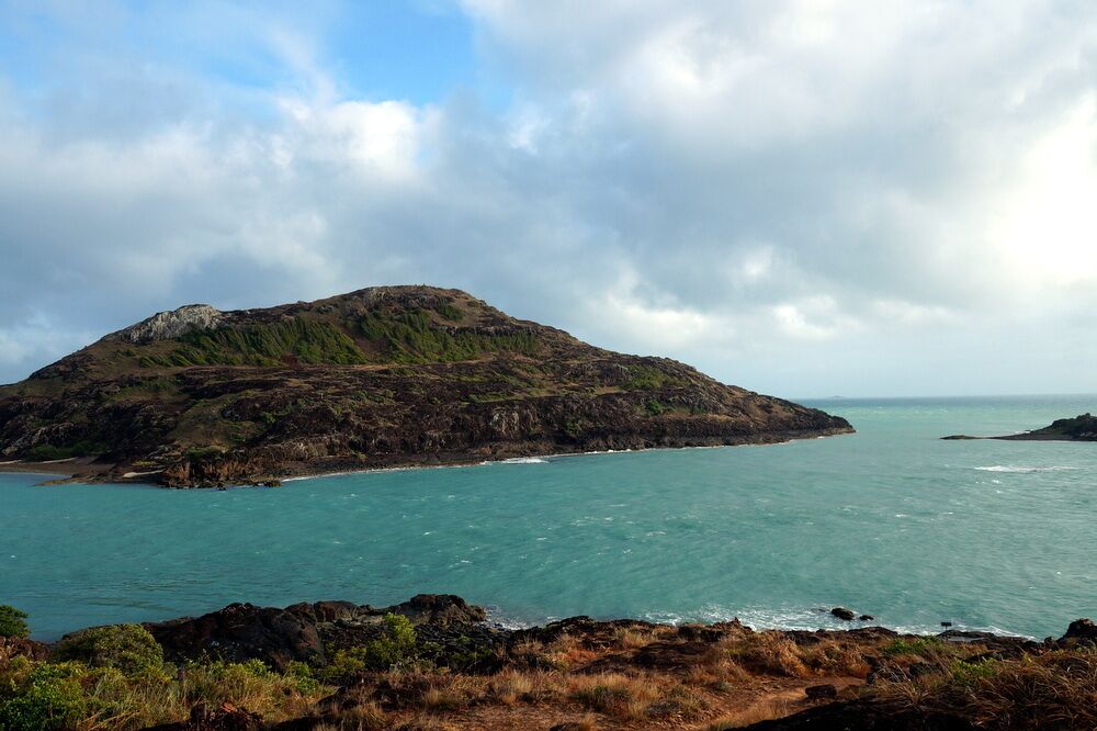 Pajinka is the northern most point of Mainland Australia, also known as "The Tip". 

Getting here is an epic journey - especially if you drive. The trip up the Cape York Peninsula is dry and dusty and can only be done during the dry season (Australian winter) - the roads are impassable during the wet season.

But all those bumps on the road are forgotten when you reach The Tip. There is a small sign on the rocks that acknowledges your achievement. 

We rose before dawn and drove from Loyalty Beach (about 40km away) to be here just after 7am. The early start is definitely worth it. By the time we were back down from The Tip the car park was full and there were 4WDs and motorbikes on the beach to the west - not the best for photos.

The actual tip is about a 1.5km walk from the car park. If you come at low tide (recommended) you can walk around the beach and climb up the roads, otherwise follow the path behind the car park up the rocks and you'll see the little cairns built with rocks. You'll spot the sign on the water's edge.