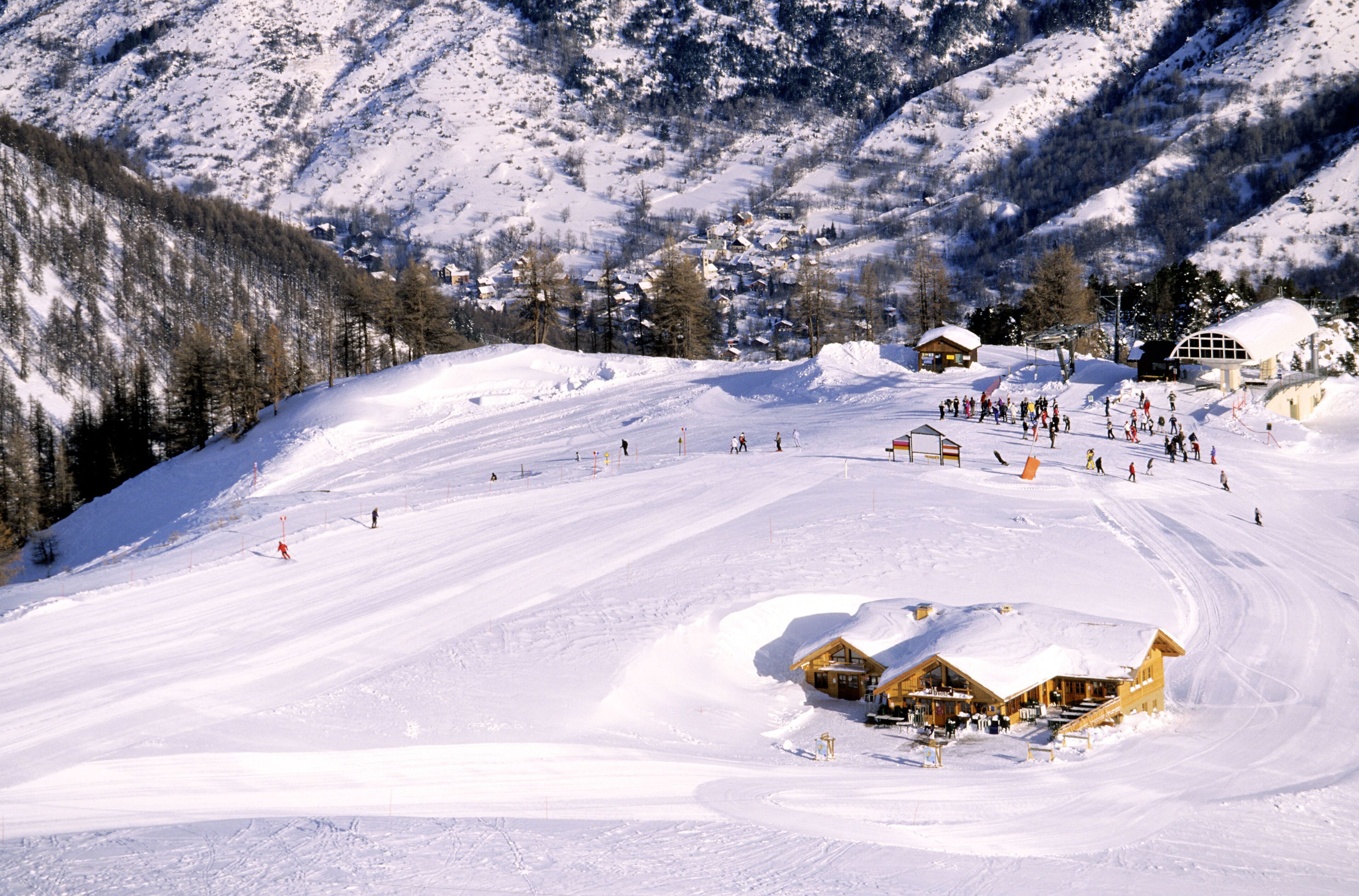A snow-covered ski resort with a ski lift, a lodge, and a mountain backdrop.