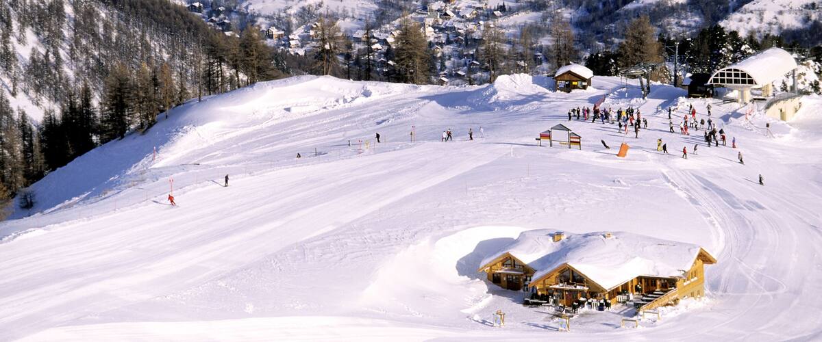 A snow-covered ski resort with a ski lift, a lodge, and a mountain backdrop.