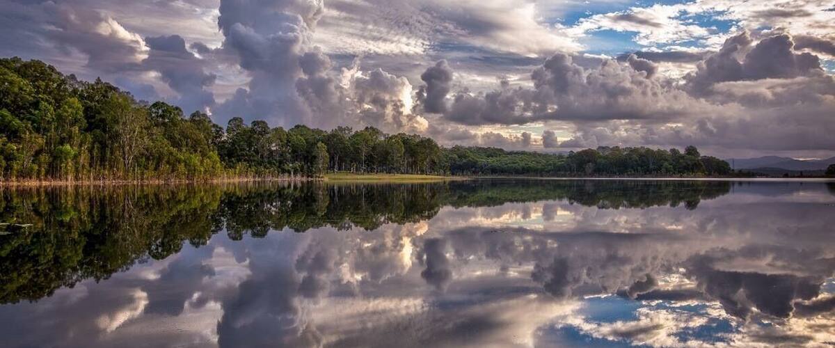 A calm lake reflecting clouds and trees.
